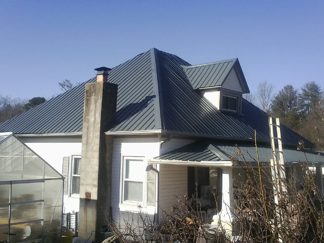 Dark blue standing seam metal roof on a white farmhouse with dormer — Slate & Tile Roof Repair by Roofing Brothers in West Linn