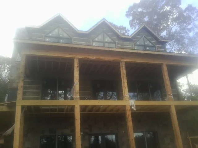 Dormers and porch framing on a large log home under construction — Roof Coating work by our crew in West Linn