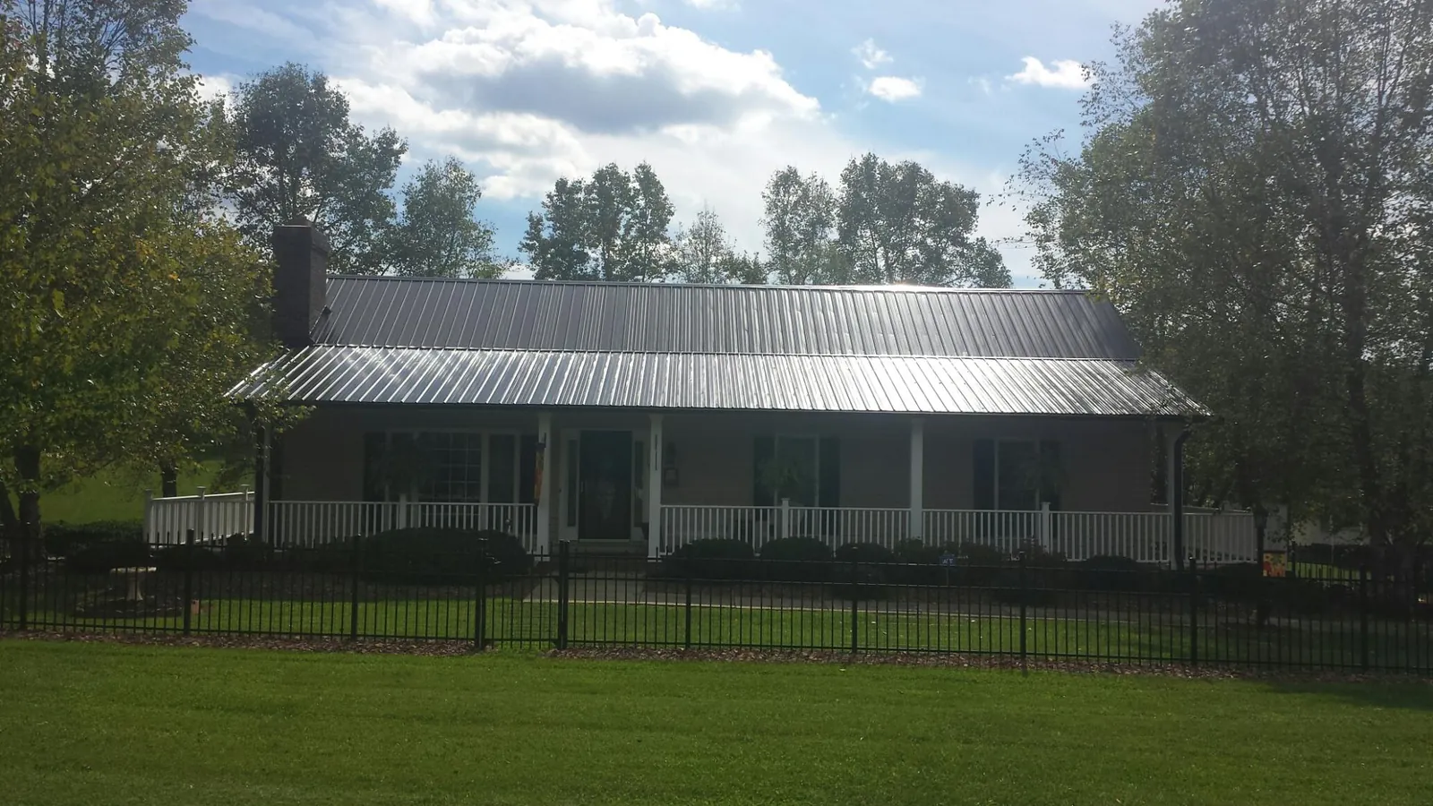 Gray metal roof on a brick ranch with a full width front porch — Gutter Guard Installation work by our crew in West Linn