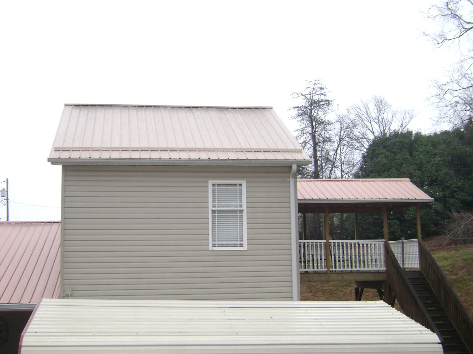 Tan metal roofs on a two story addition and attached porch, from a Roof Replacement job in West Linn