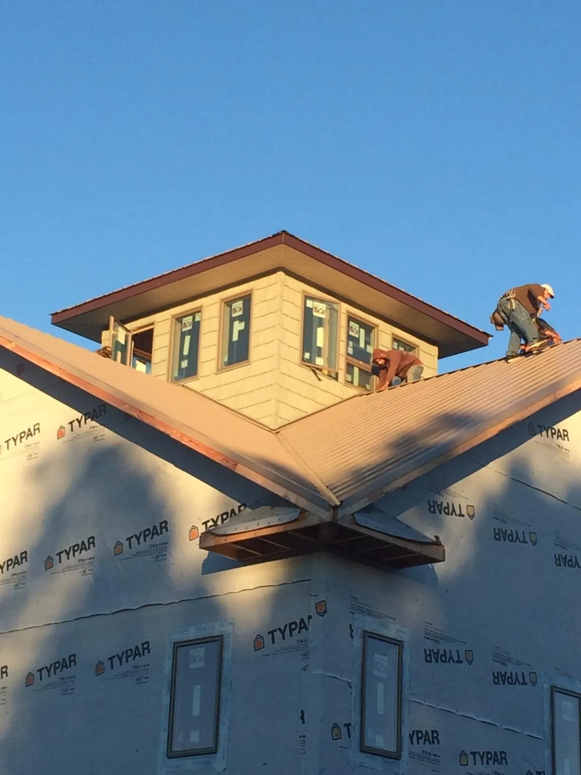 Roofers working around a rooftop cupola on a new metal roof at sunset — Roof Waterproofing in West Linn by Roofing Brothers